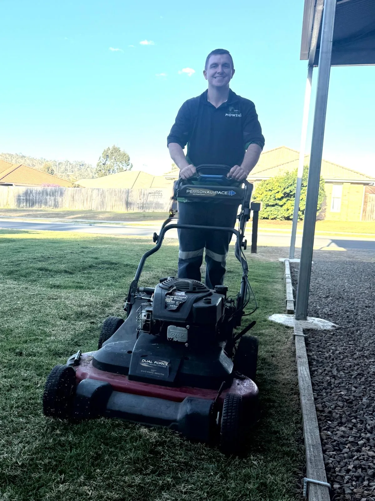 Johnross behind a wide-deck mower on a Fernvale front lawn
