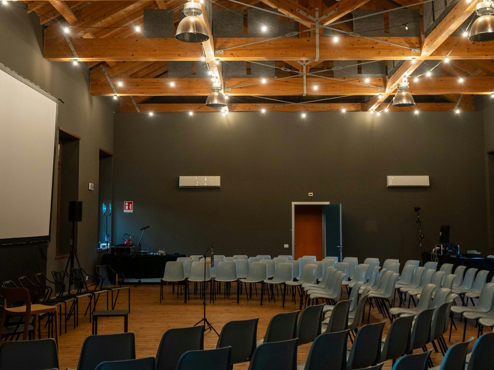 Stock photo, not the church's hall: a timber-trussed hall with stacking chairs and a projector screen
